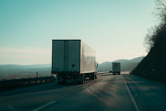 Camions de transport de marchandises roulant sur une route de montagne sous un ciel clair