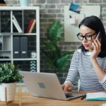 jeune femme travaillant sur son ordinateur en train d'appeler un client pour le relancer de payer une facture en attente de règlement