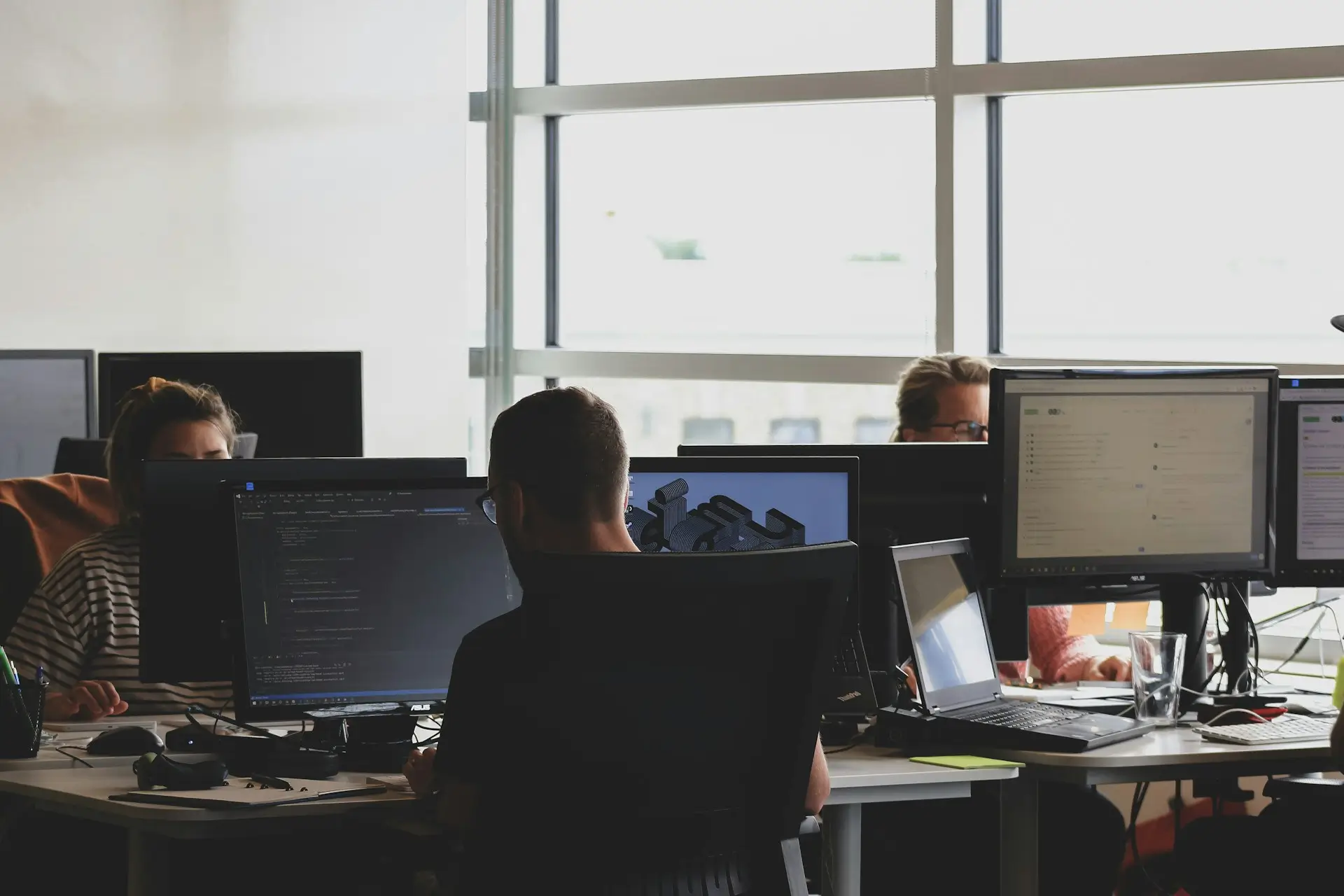 Un professionnel souriant au téléphone devant son ordinateur portable dans un bureau moderne, représentant un échange fluide avec un client grâce au suivi de facturation de CashNow