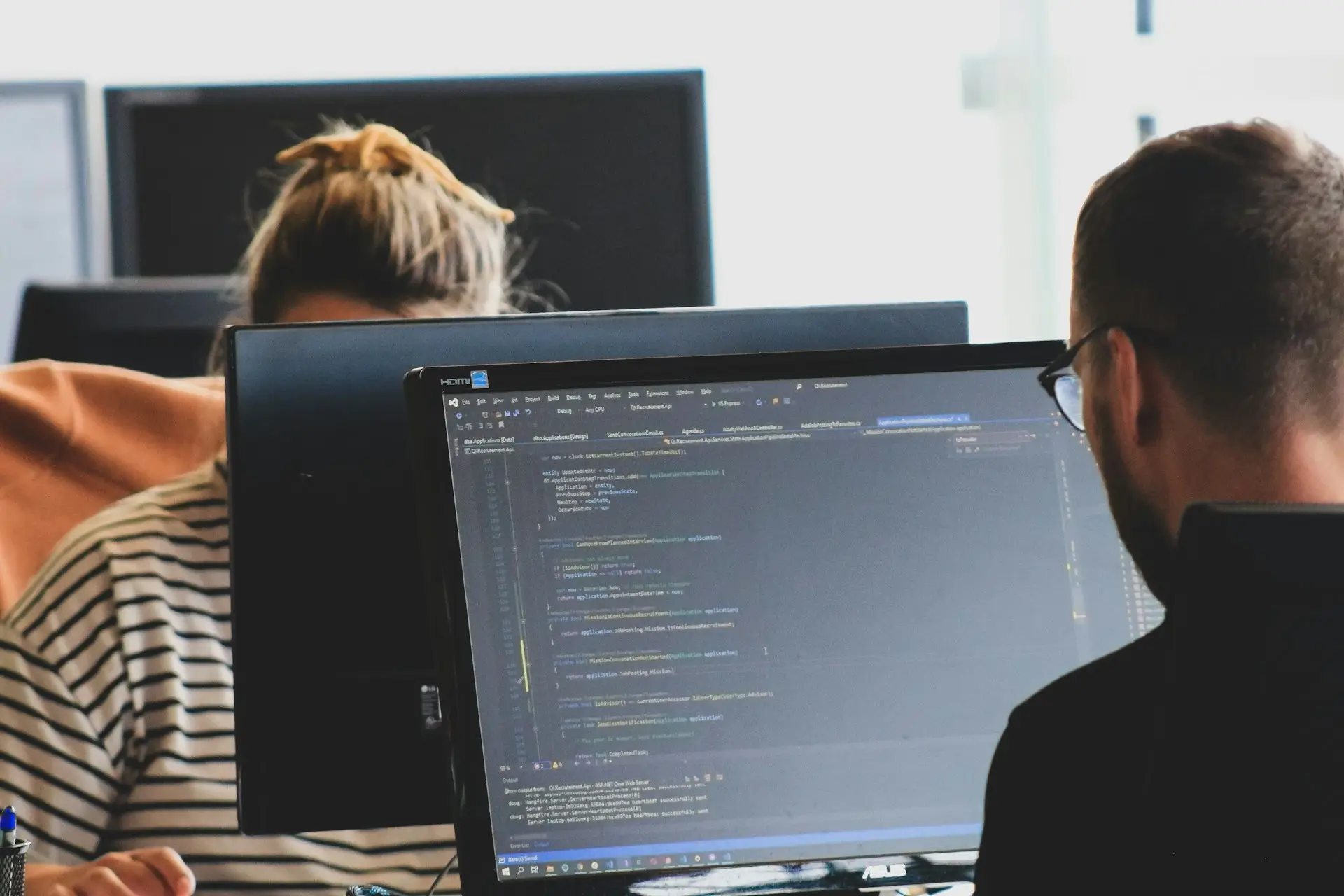 Un professionnel souriant au téléphone devant son ordinateur portable dans un bureau moderne, représentant un échange fluide avec un client grâce au suivi de facturation de CashNow