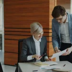 Une femme et un homme dans une entreprise en train de vérifier un document ensemble
