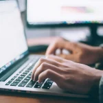 Mains en train de taper sur le clavier d'un ordinateur portable