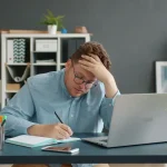 employé comptable en train de se prendre la tête avec une main